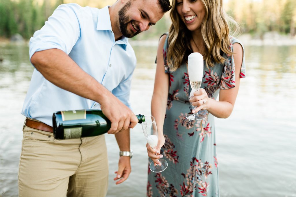 a man pours some champagne in a glass while his fiance smiles