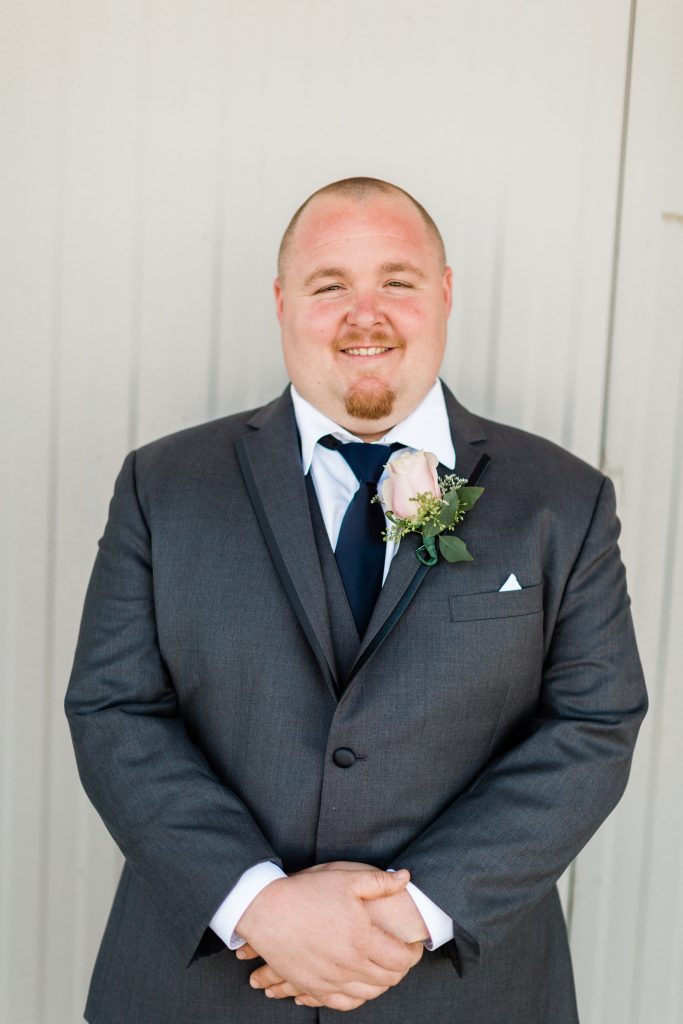 groom in grey suit with navy tie and pink rose boutonniere