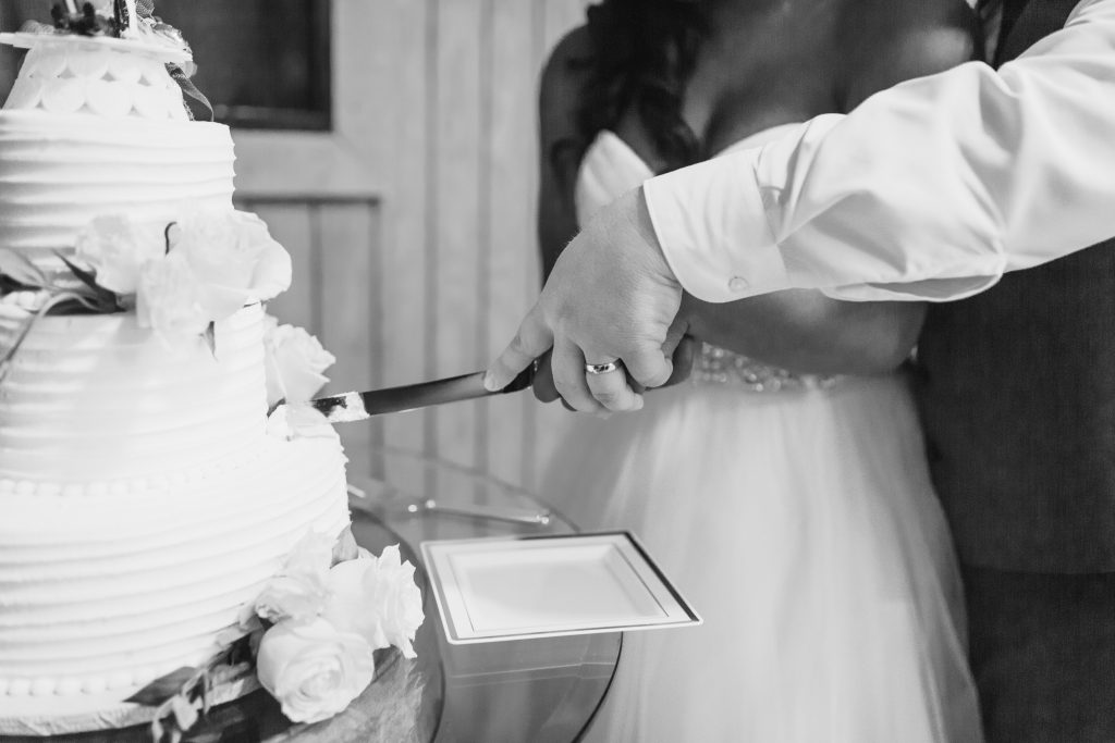 bride and groom cutting wedding cake in black and white