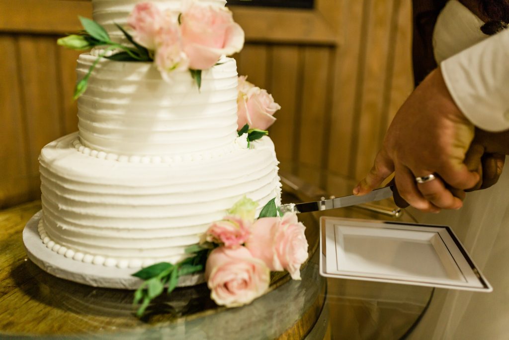 cake cutting ceremony with white cake and pink roses