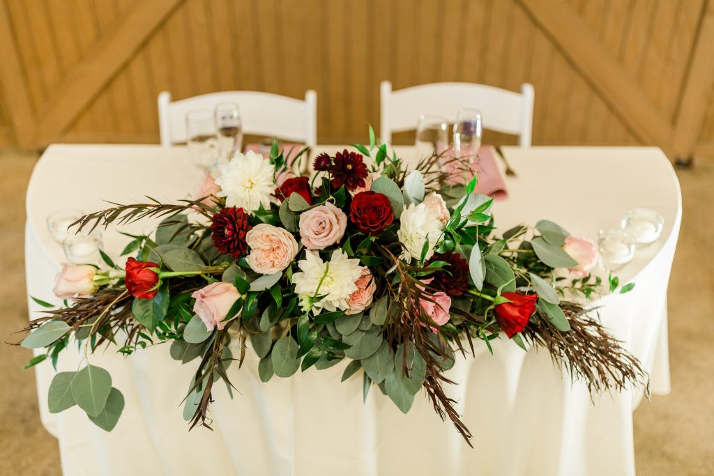 blush and rich red sweetheart table floral arrangement