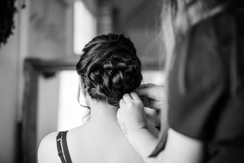 black and white of a hair stylist pinning a brides hair in place