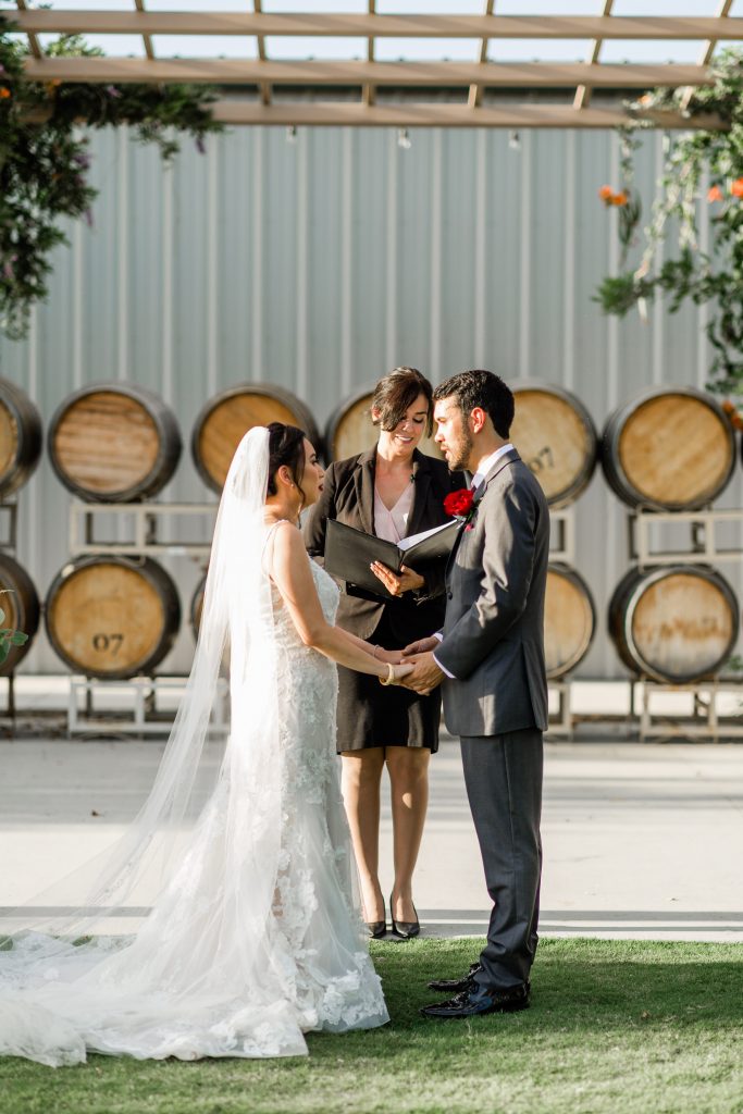 couple holding hands during their wedding ceremony at a winery