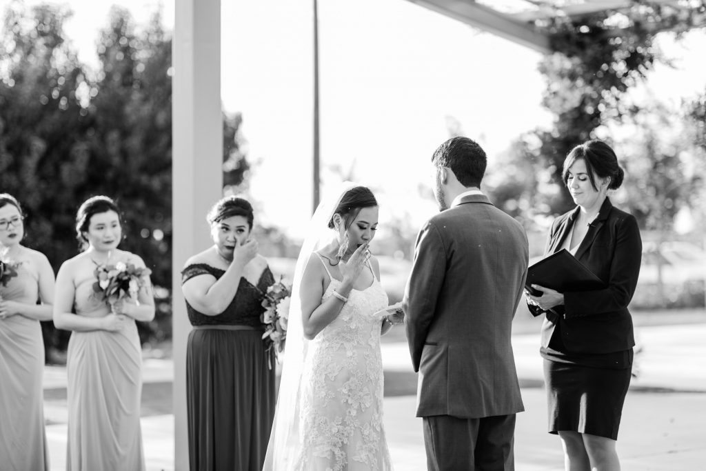 black and white moment of a bride getting emotional as she reads her wedding vows to her groom