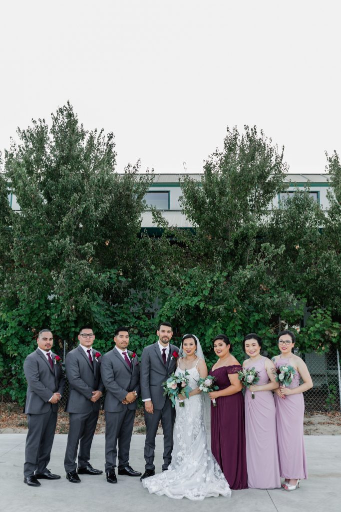 formal wedding party with guys in grey suits with burgundy ties and bridesmaids in mauve maxi dresses and the maid of honor wearing a burgundy maxi dress