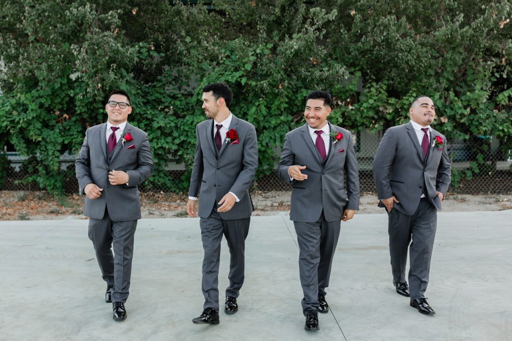 groom and his groomsmen in grey suits walking and smiling