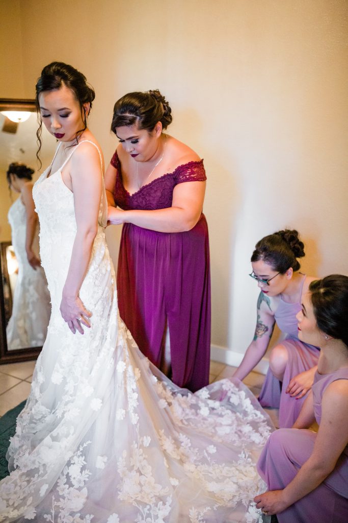 bridesmaids helping the bride into her wedding dress at a winery