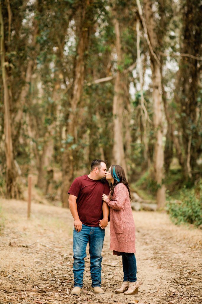 fall engagement photos of a couple standing underneath eucalyptus trees