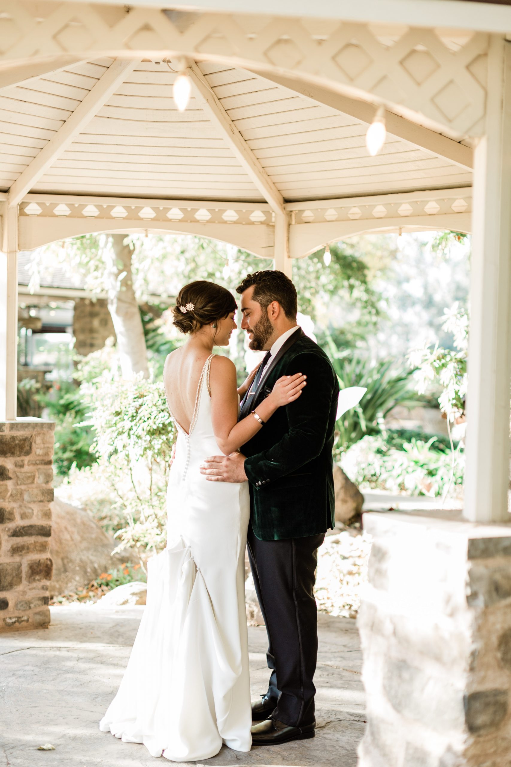 bride and groom embracing under white gazebo at wolf lakes park a fresno wedding venue