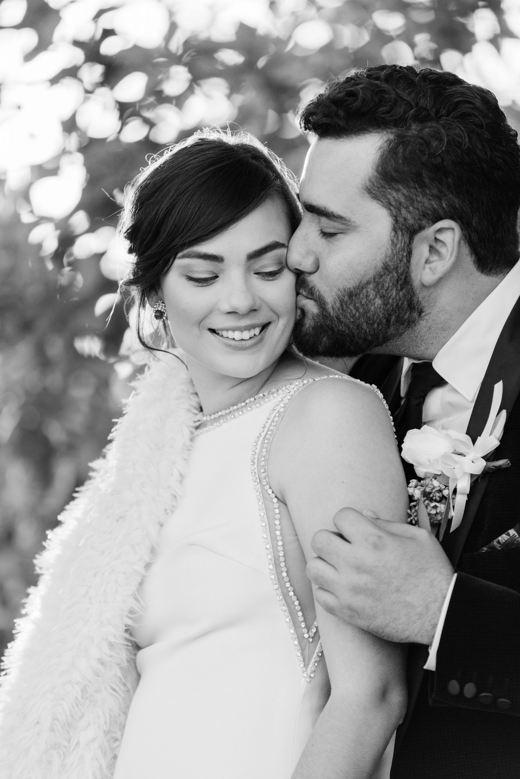black and white photo groom kissing bride on cheek