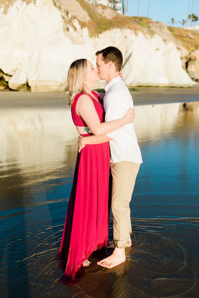 engaged couple kissing on the beach at sunset