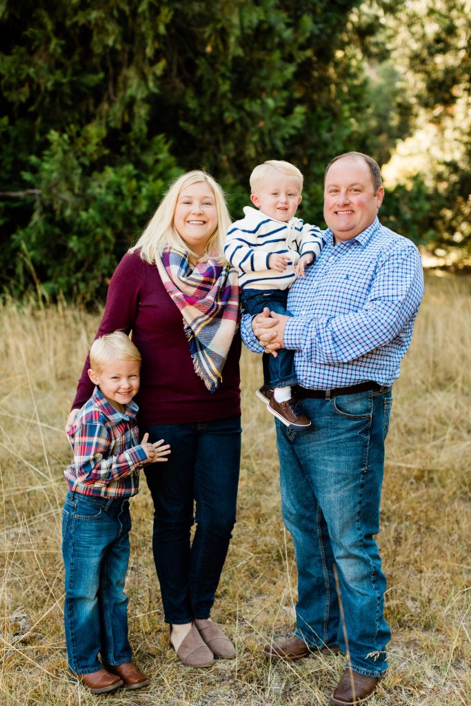 fall family photos in a meadow of dried grasses with evergreen trees in the background