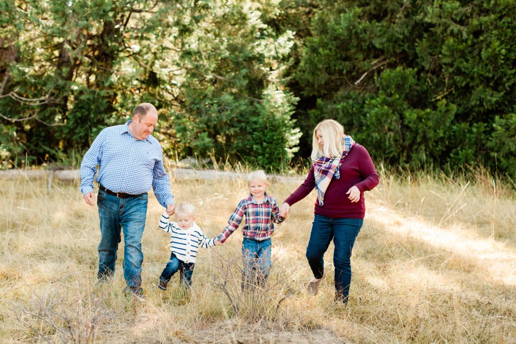 family holding hands and walking through a meadow in the fall