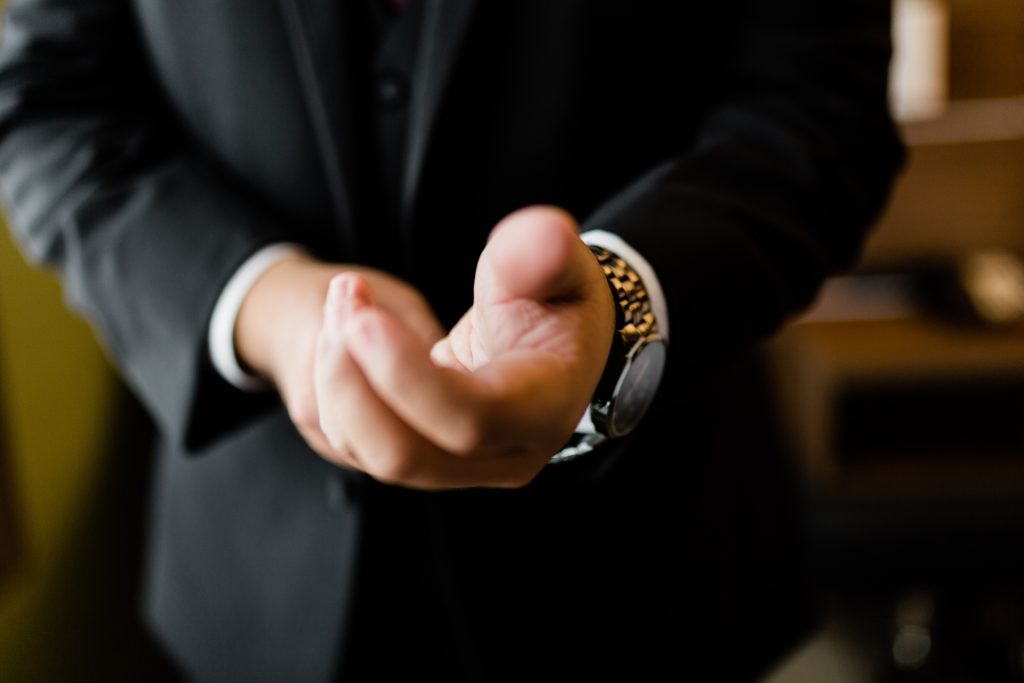 man in a black suit putting on a watch