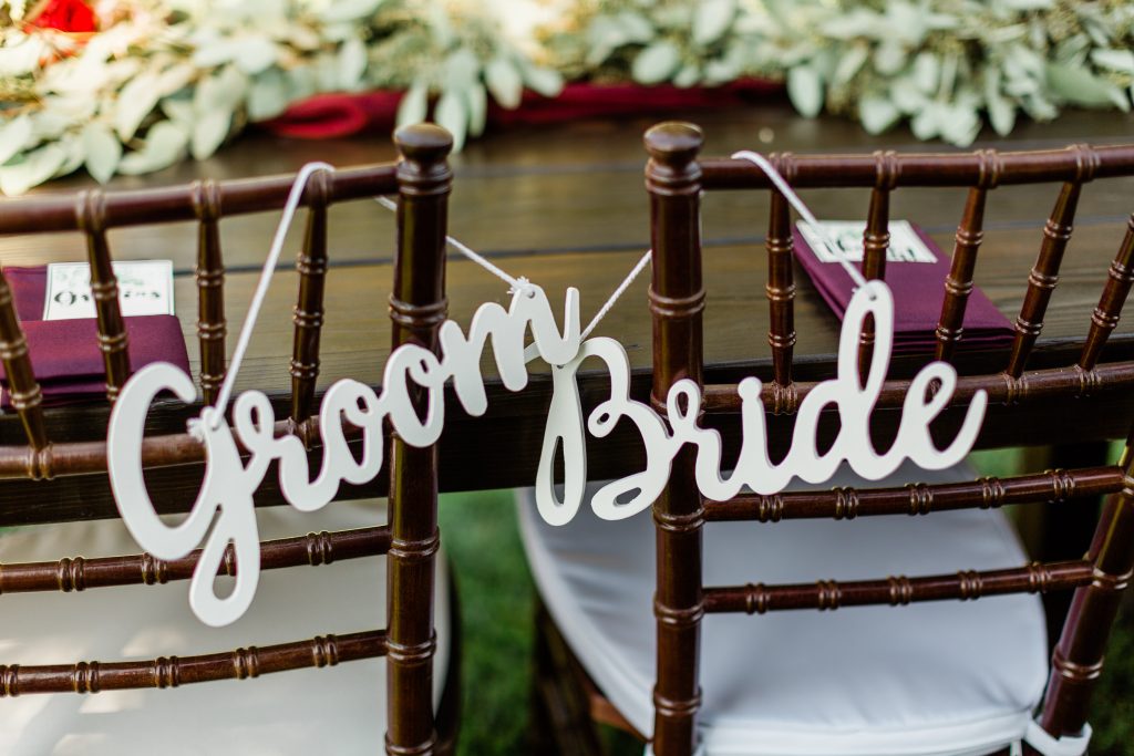 white wooden bride and groom signs hanging on cherry wood chairs