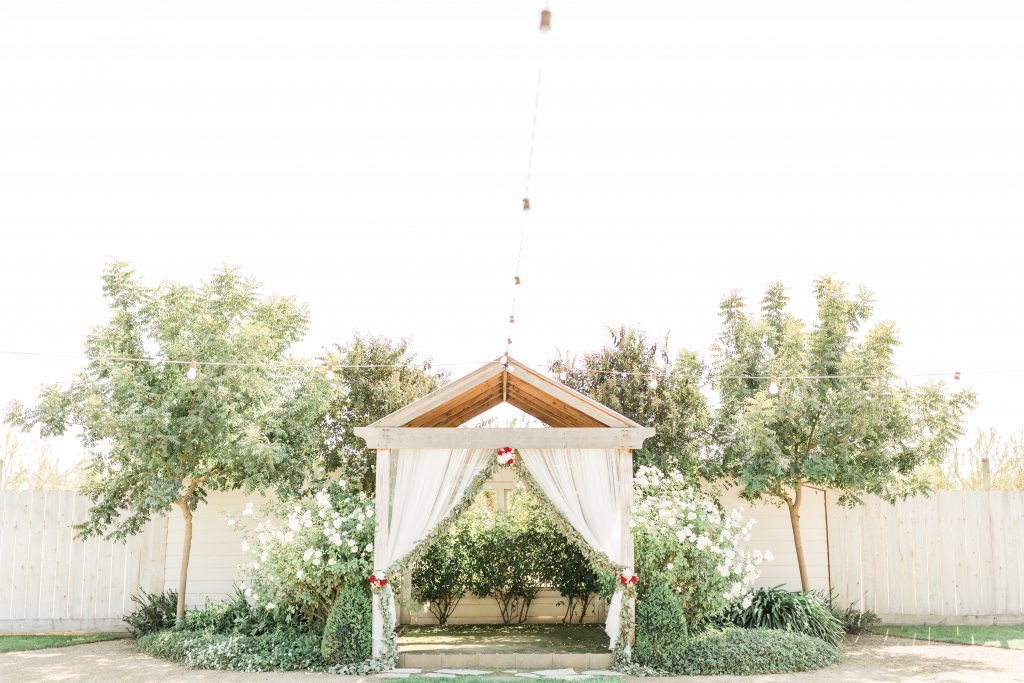 r wedding house ceremony arbor with white curtains and greenery
