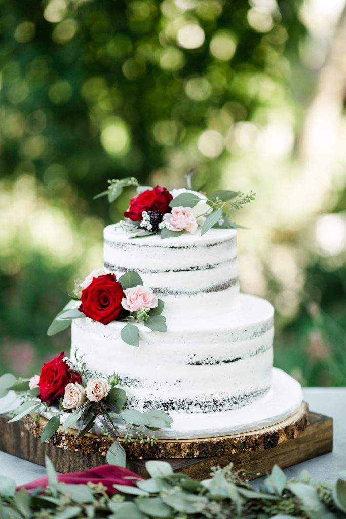 naked chocolate cake with red and blush flowers