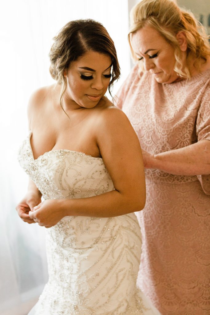 brides mom helping her zip up her wedding dress