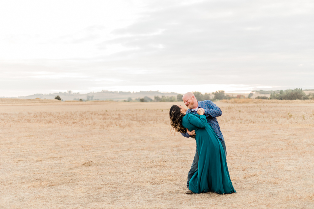 engaged couple dancing in an open field