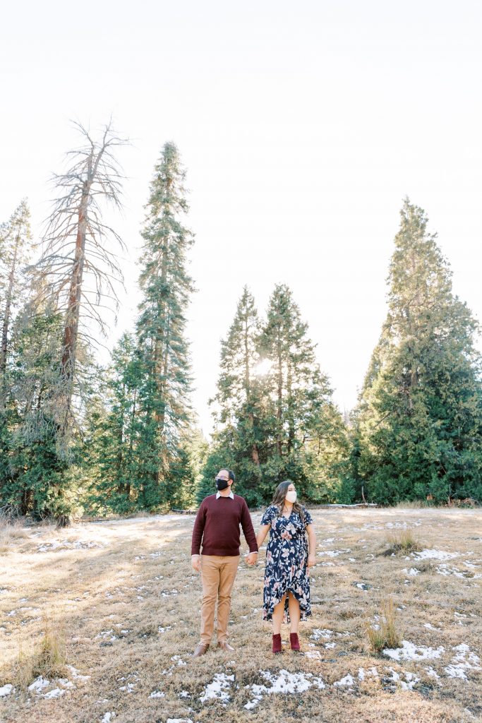 couple holding hands standing in a meadow wearing masks by fresno wedding photographer megan helm