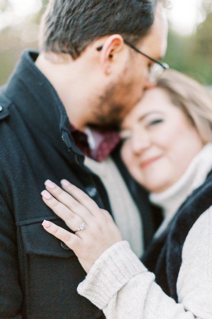 engagement ring with couple blurred out in the background