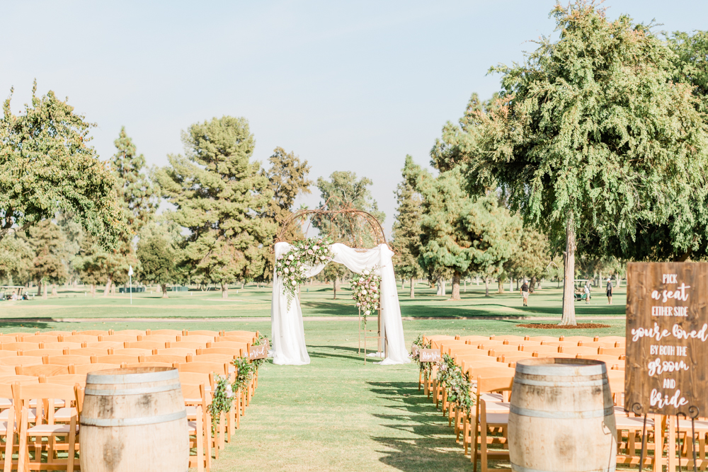 outdoor ceremony site with arch draped in white fabric and flowers