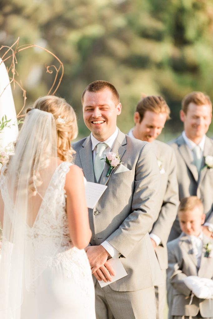 Groom laughing while bride says her vows
