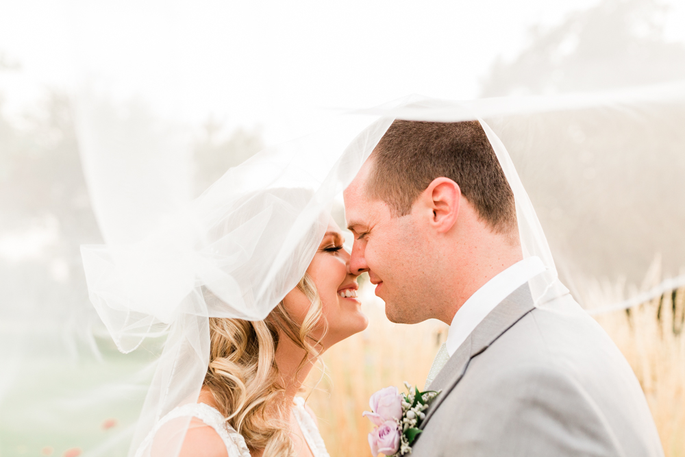 Couple nose to nose under flowing veil at country club wedding