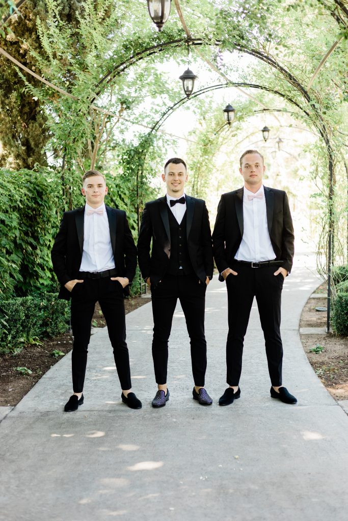 groom and his groomsmen in black tuxedos with bow ties