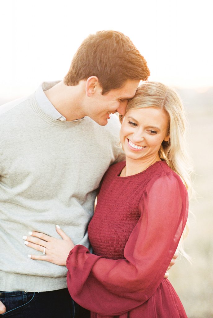 man nuzzling in to woman during fall engagement photos