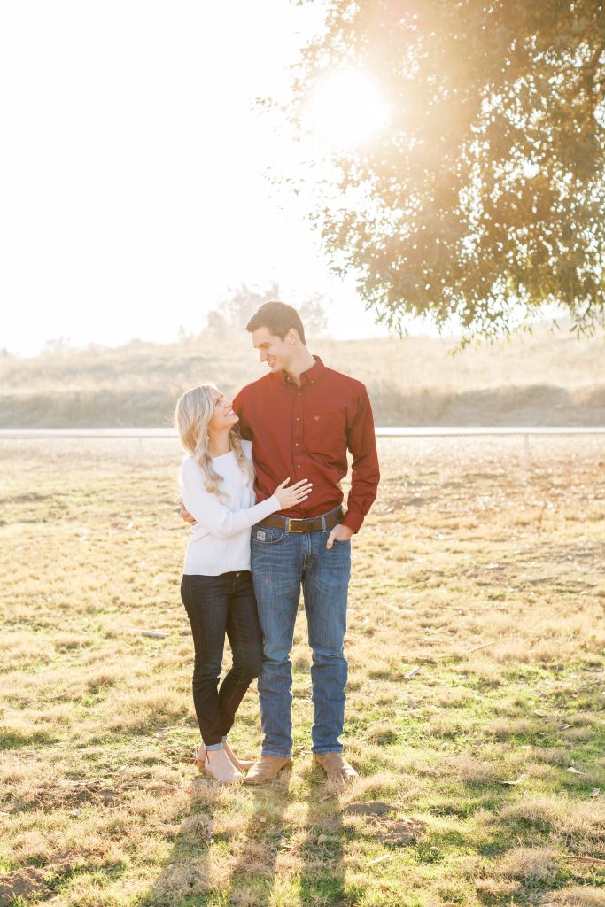 couple standing in the grass for fall engagement sunset photos