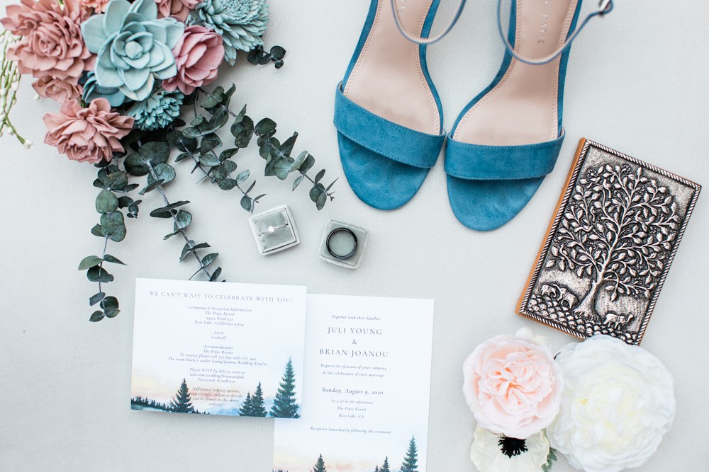 Close up of wedding shoes, rings, flowers, and vow book