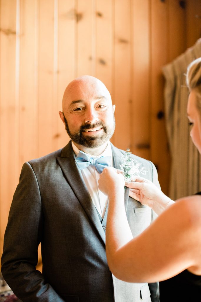 Groom smiling while boutonniere is put on