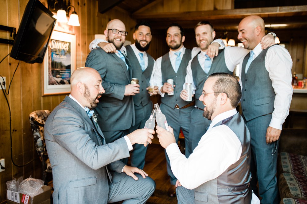 Groomsmen huddled to have a cheers drink pre Bass Lake wedding