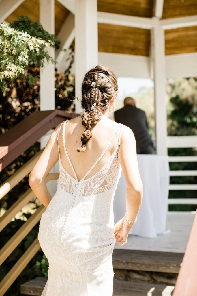 Bride walking up in with fishtail braid and low back beaded dress
