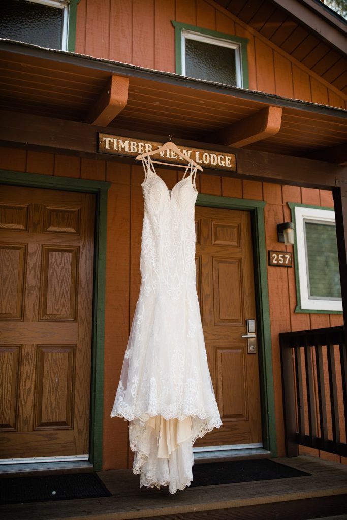 Wedding dress hanging in front of wood lodge