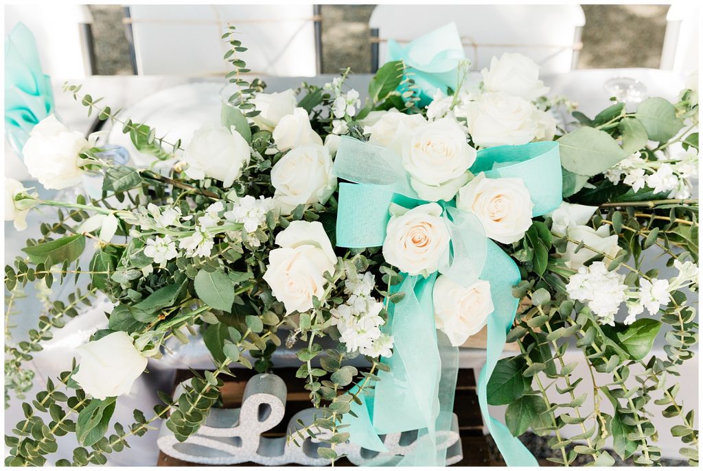White flower centerpiece with eucalyptus and teal bows