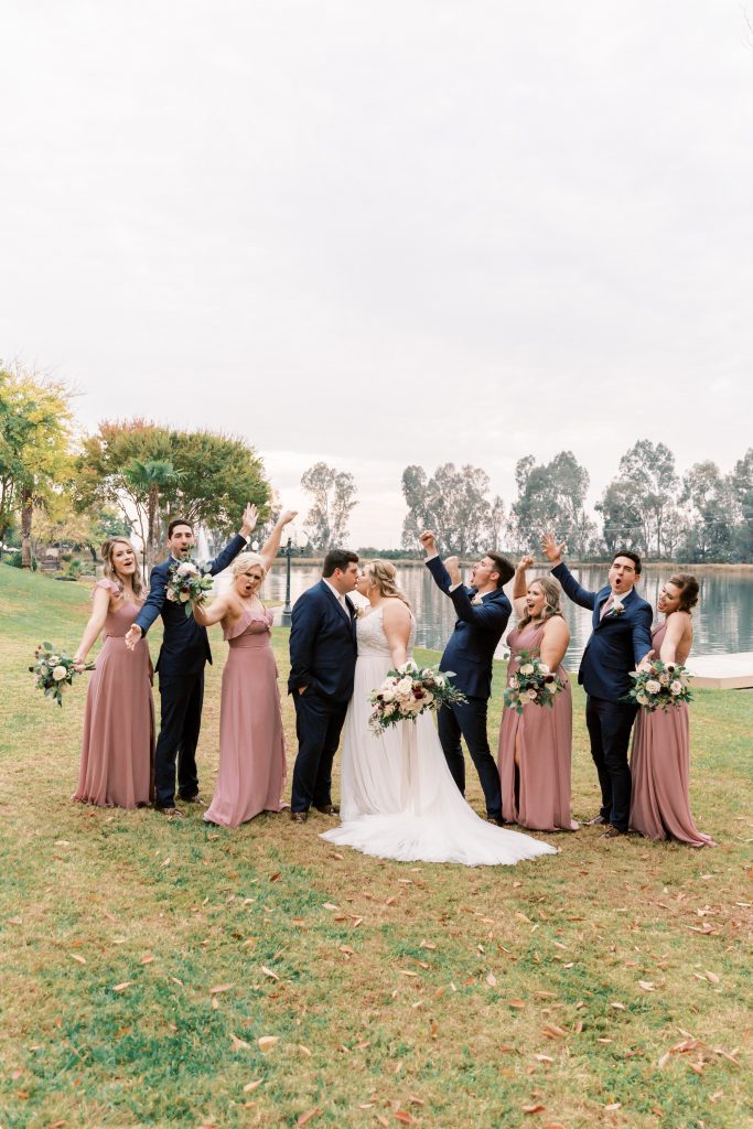 Blush and navy wedding party cheering for Bride and Grooms kiss