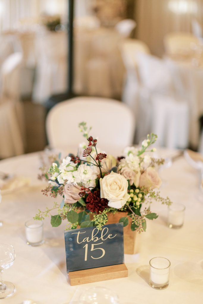 White, green, and burgundy centerpiece with gold table number