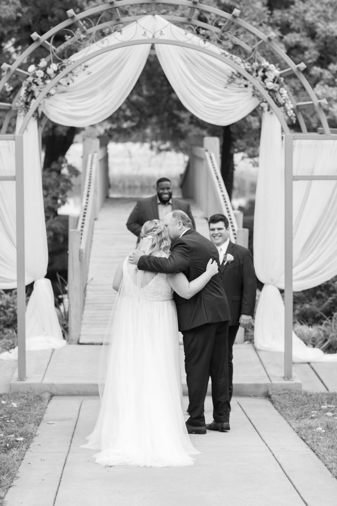 Father kissing bride to hand her to the groom in black and white photo