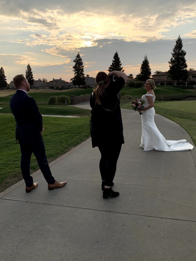 Photographer capturing bride during sunset while groom admires