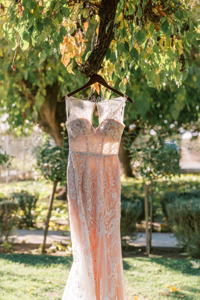 Lace wedding dress hanging from Bride hanger in a tree