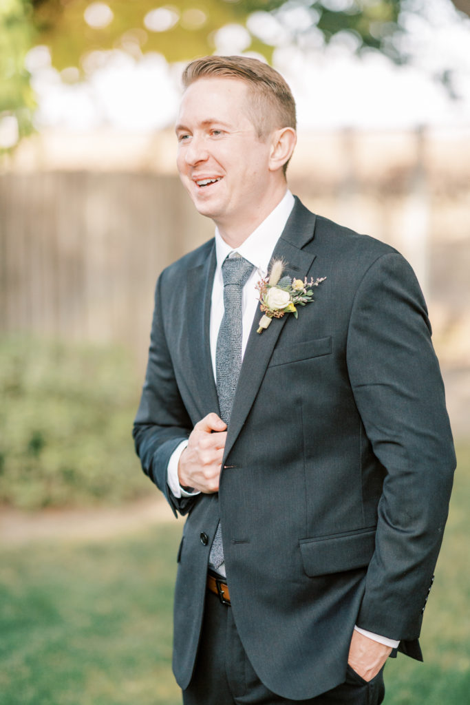 Groom laughing and holding on to his suit jacket.