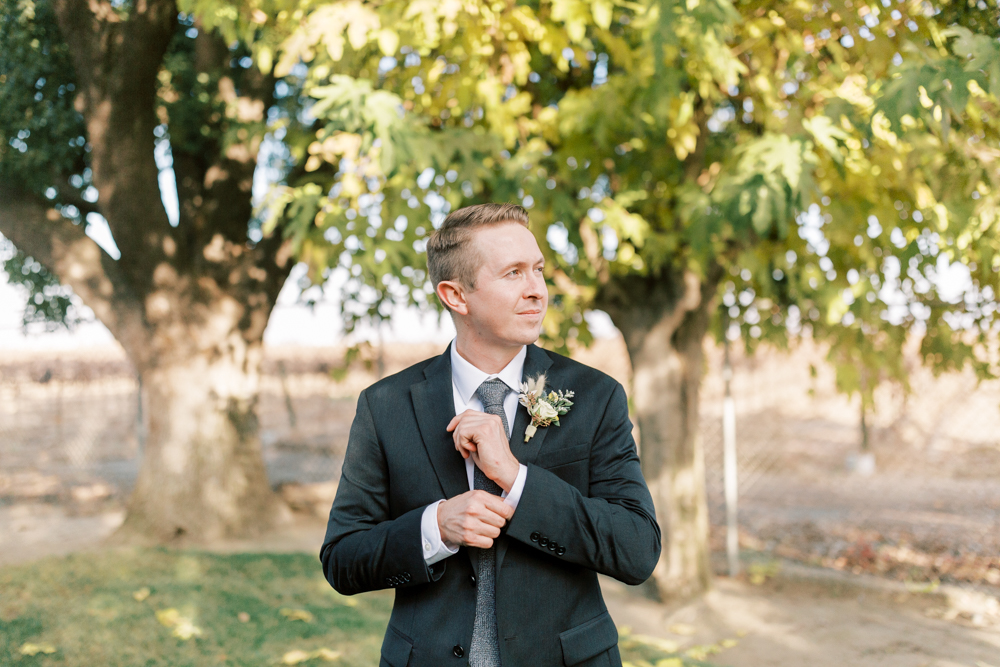 Groom fixing his sleeve in a charcoal suit