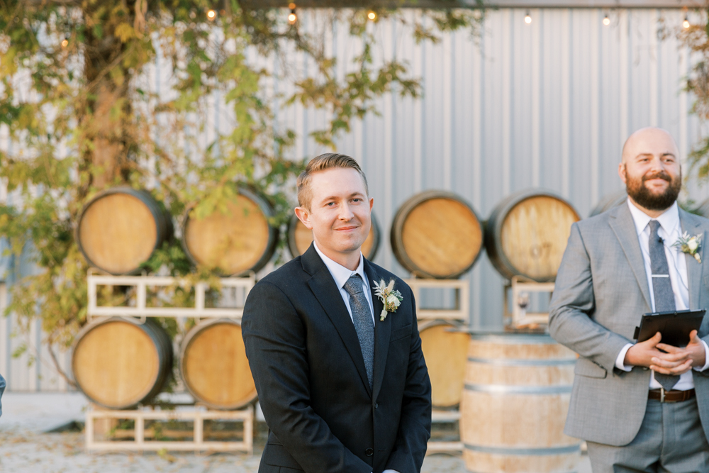 Groom waiting at the altar with the officiant at a Kings River Winery wedding