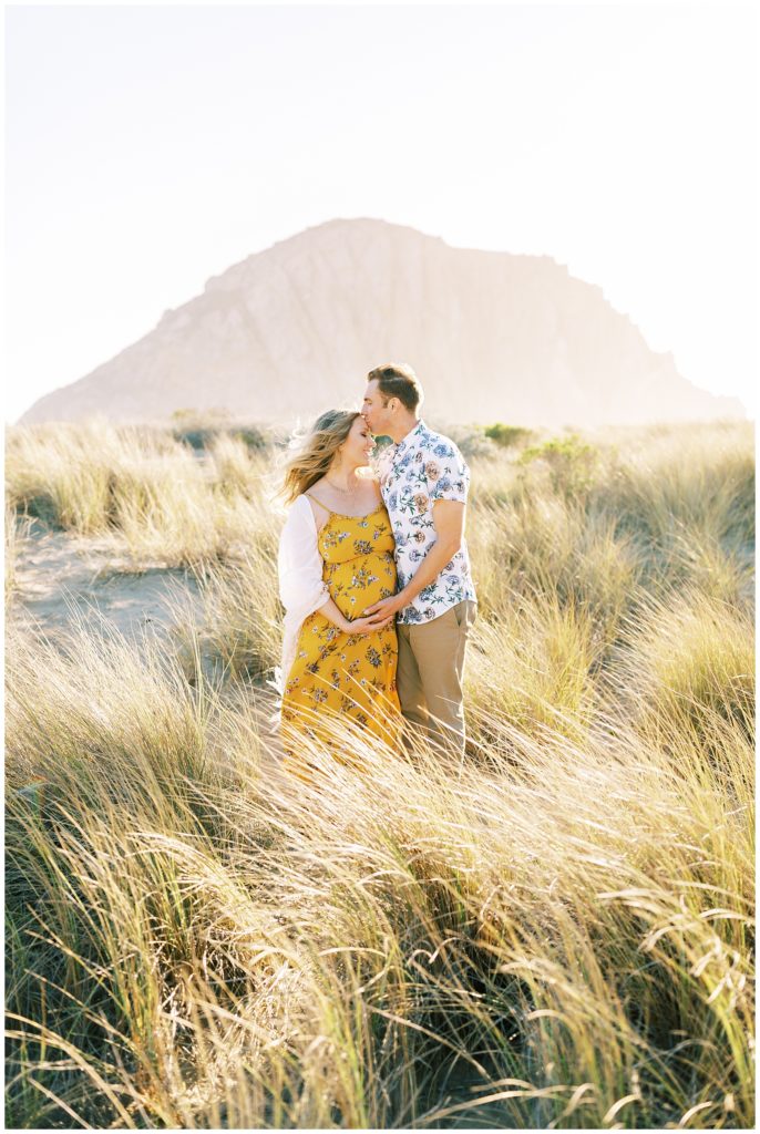 Couple embraced while standing in the grass in Morro Bay