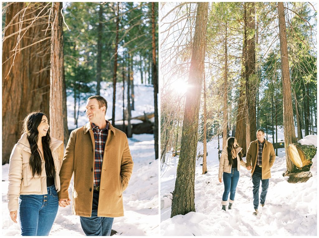 Engaged couple holding hands while walking among tall trees