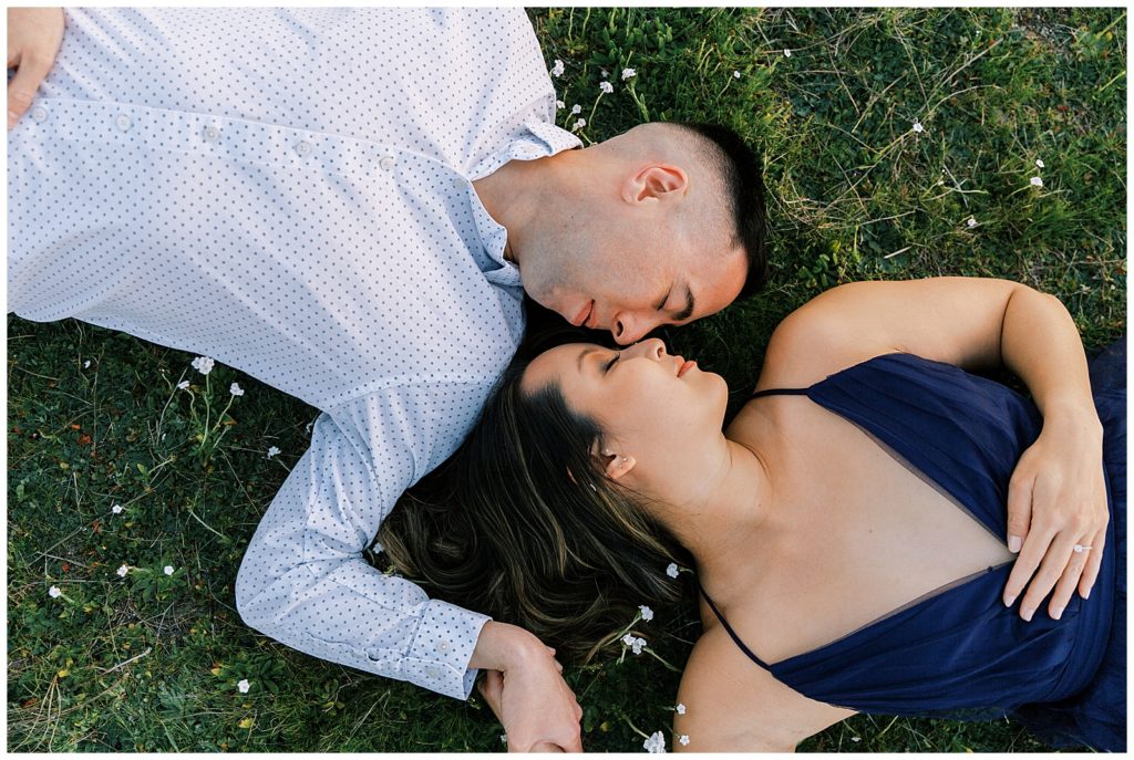 Engaged couple laying in the grass 