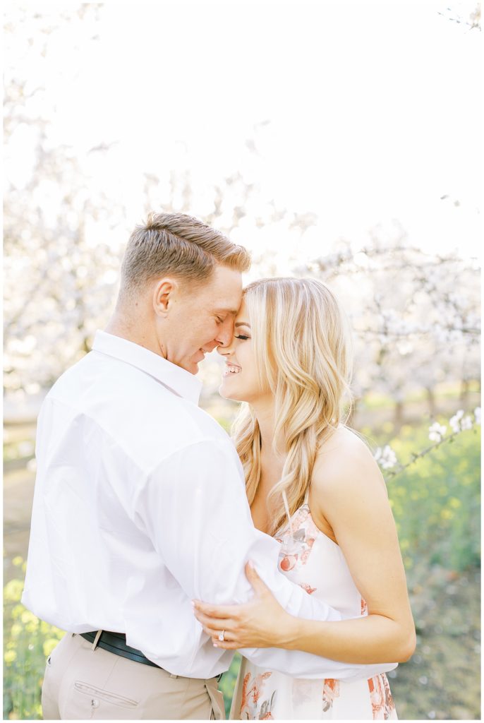 Couple touching foreheads and laughing during spring engagement photos