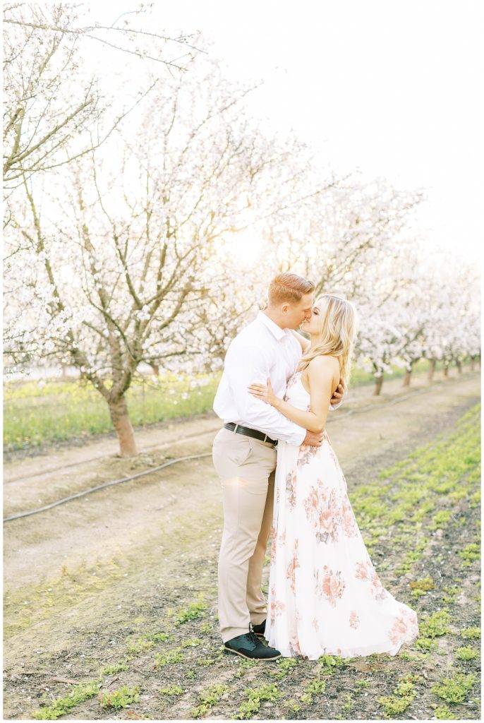Couple kissing among the blossom trail for spring engagement photos